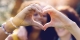 Mixed race couple make heart sign as a symbol of unity